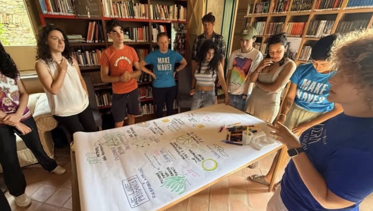 Students around a long paper sheet of drawings and slogans for Posidonia