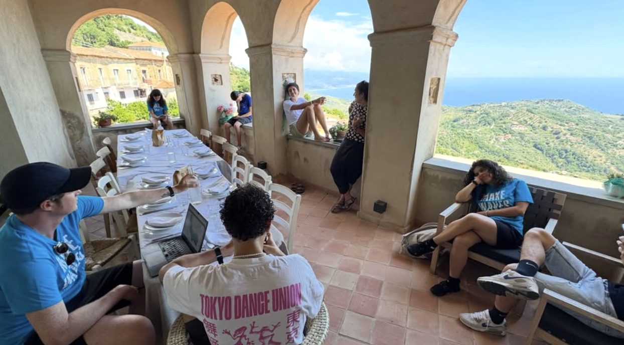 Lunch laid on a long table under the arches of the campus terrace, the coast and the sea beyond